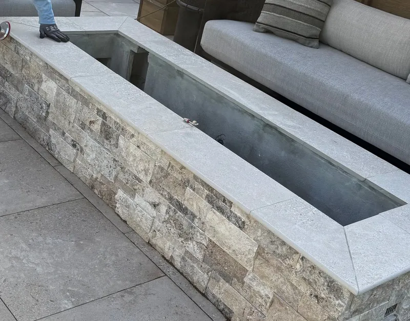 Stone water feature and built-in bench on a travertine patio
